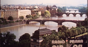A QSL card showing an aerial view of Prague in the 1980s, with three bridges across the Vltava River (bottom left to center-top right)